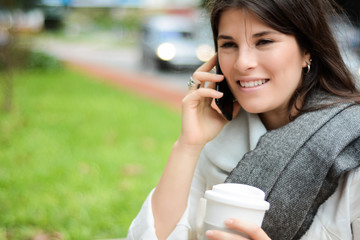 Young latin woman with her mobile phone and cup of coffee