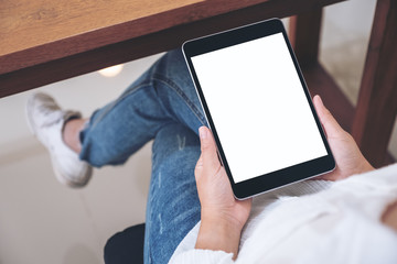 Mockup image of a woman holding black tablet pc with blank white screen while sitting in cafe