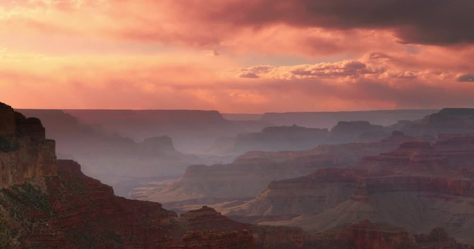 Dramatic shot of Grand Canyon at sunset with amazing lighting, clouds, red cliffs and blue skies in 4K DCI.