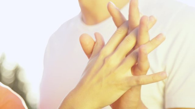 CLOSE UP, DOF: Unrecognizable teenage couple gently interlocking their fingers while enjoying a romantic date in the sunny nature. Young lovers playfully holding hands and intertwining their fingers.