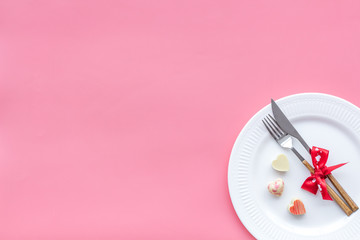 Dating on Valentine's day concept. Festive dishes, tableware on plate on pink background top view copy space