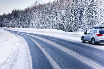 Suv car with rooftop cargo carrier trunk stay on roadside of winter road. Family trip to ski...