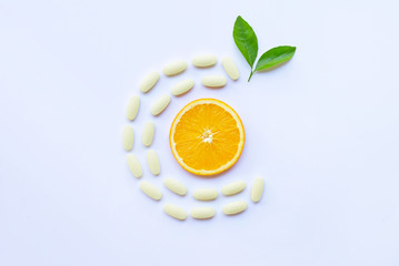 Vitamin C  pills with orange fruit on white.