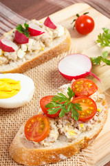 Fototapeta na wymiar Crispy sandwiches or baguette with mackerel or tuna fish paste on cutting board