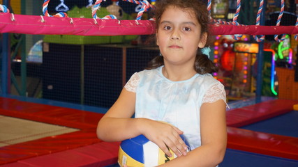 Little girl near the volleyball net with ball in her hands