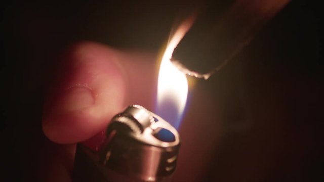 Macro Lens: Hand flicks lighter flame to light a stick of Palo Santo on fire