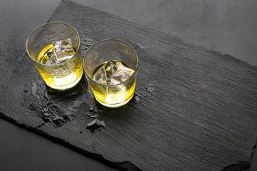 In the bar. Whiskey with ice on black desk on black background top view copy space