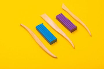 two Bars of plasticine and cutters are isolated on a yellow background