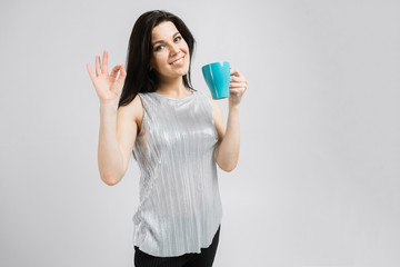 young girl with a turquoise mug stands isolated on a light background