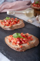 Bruschetta sandwiches with tomato, basil leaf and garlic on gray board as background