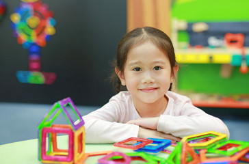 Fototapeta na wymiar Little child girl playing Magnets toy for brain development.