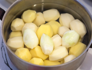 peeled raw potatoes in a saucepan on the table.