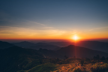 Dramatic sunset and sunrise with sun flare over mountain valley morning twilight evening sky.