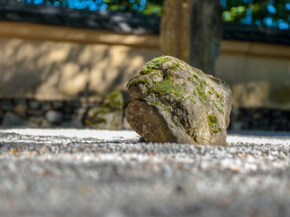 Close up view at a stone on a ground a of garden of stones. Stone shape, colors and surface make it look like a human face