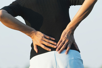 Fototapeta na wymiar Closeup hands of woman touching her back pain in healthy concept on nature background.