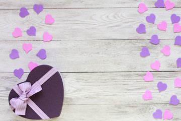 Heart shaped gift box and small lilac and pink hearts on white wooden boards. Valentines day concept. Border, copy space, confetti, wrapping, present