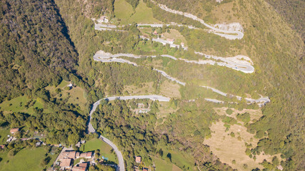 Fototapeta premium Up and down drone aerial view of the mountain road in Italy from the village of Nembro to Selvino. Amazing aerial view of the mountain bends creating beautiful shapes