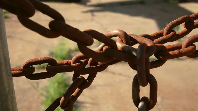 Rusty chain locking a fence at abandoned closed factory