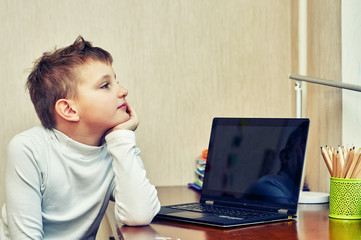 Brooding primary school student at the laptop . Concept of education