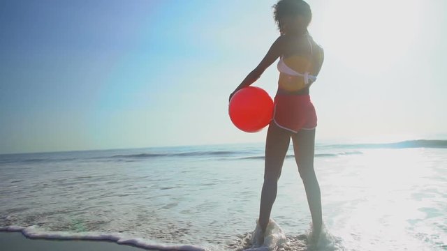 Happy ethnic woman posing on vacation beach with red ball