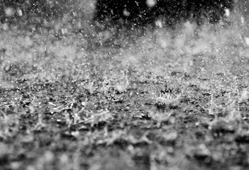 Black and white image of a raindrops splashing on a concrete surface