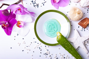 A set up of wellness items, a candle, stones, a beauty sponge, a sea star, towel, flowers, a natural sponge, aloe vera leave, aloe vera gel, wood, a bamboo mat, decorative stones
