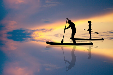 couple standing on a paddle at sunset