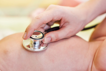 The baby is examined by a doctor. The doctor listens to the lungs and heart with a stethoscope. Close-up, small DOF