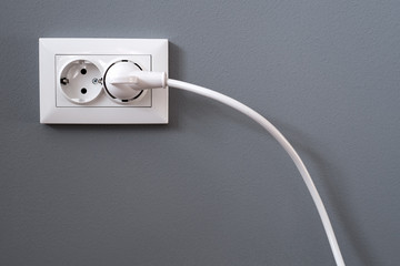 Power cord cable plugged into wall outlet