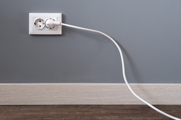 Power cord cable plugged into wall outlet