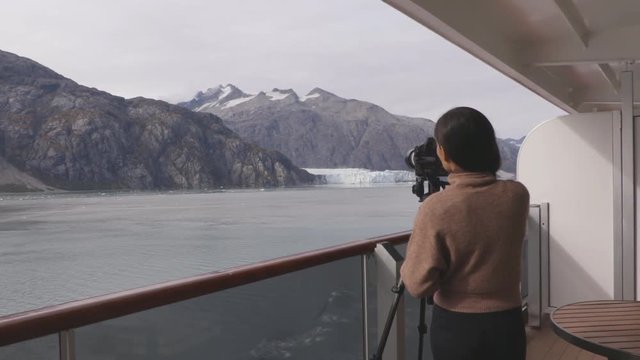 Photographer tourist in Alaska. Cruise ship passenger photographing glacier, Glacier Bay National Park, Woman taking photo with SLR professional camera equipment on travel vacation. Margerie Glacier.