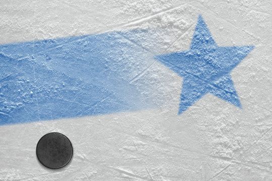 An image of a blue line with a blue star on ice and a hockey puck