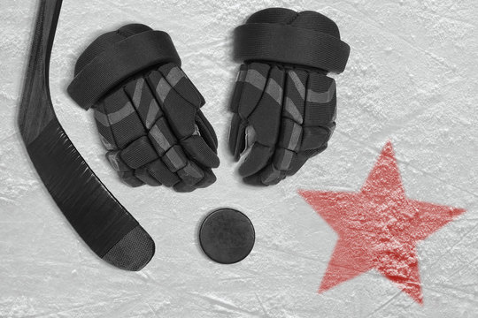 An image of a red star on ice and hockey accessories