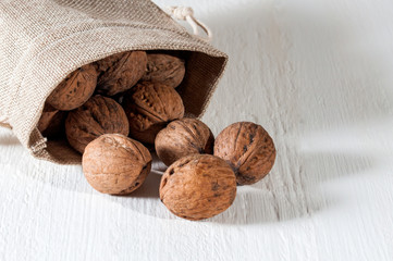 Walnuts in sack on white wooden background. Healthy food and health care. View from above.