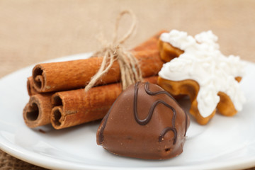 Chocolate candy on white plate with cinnamon and cake.