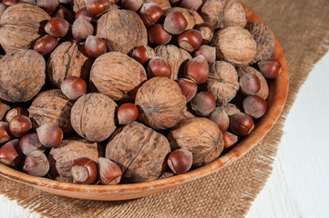 Walnuts and hazelnuts in bowl on burlap.