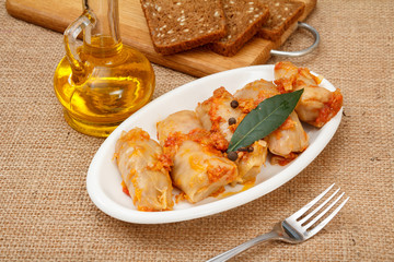 Delicious homemade cabbage rolls stuffed with rice and meat on dish with fork and bottle of sunflower oil.