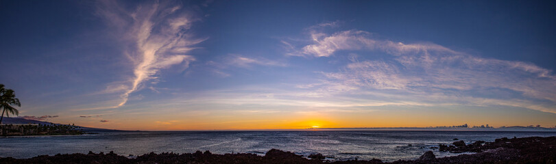Obraz premium Scenic stitched panorama of a sunset with a dramatic sky over Pacific ocean, Big Island, Hawaii. Orange, yellow and red color over the horizon with a beautiful clouds in a blue sky.