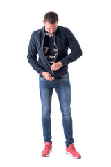 Young adult man zipping up bomber jacket zipper getting dressed. Full body isolated on white background.