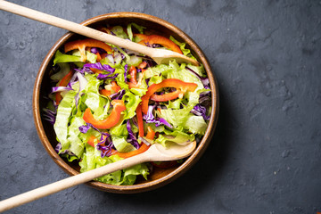 Healthy vegetable salad of fresh tomato, cucumber, onion, spinach, lettuce and sesame on plate.