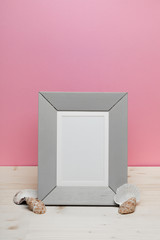 gray frame with shells on white desk near pink wall