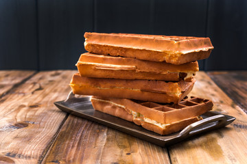 Belgian waffles on a wooden background. Homemade pastries for a family breakfast. Minimal composition. Place for text on the photo.