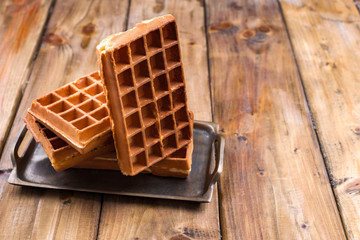 Belgian waffles on a wooden background. Homemade pastries for a family breakfast. Minimal composition. Place for text on the photo.