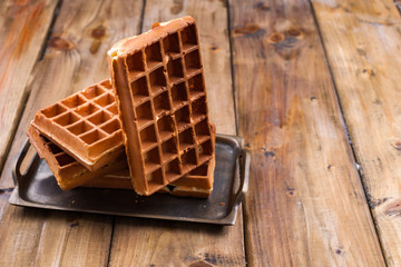 Belgian waffles on a wooden background. Homemade pastries for a family breakfast. Minimal composition. Place for text on the photo.