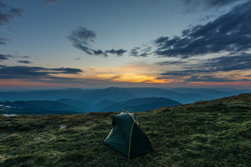 Landscape of the sunset in the Ukrainian Carpathian Mountains with a tourist and a tent.