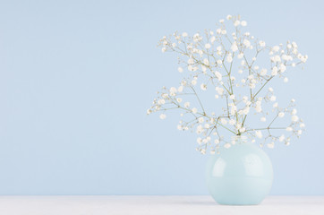 Gentle elegant bouquet of small flowers in ceramic circle bowl on soft pastel blue background. Modern minimalist spring home decor.