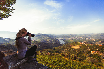 Woman photographs river, vineyards are on a hills of Douro Valley - Portugal. - obrazy, fototapety, plakaty
