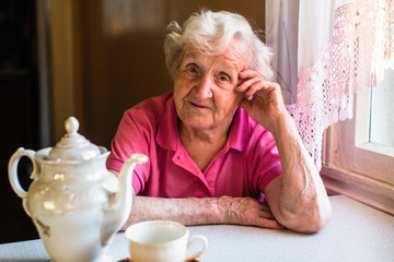 Senior lady drinks tea in her house. Pensioner woman.