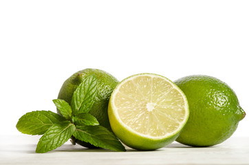 two limes with half of  juicy lime on a wooden table