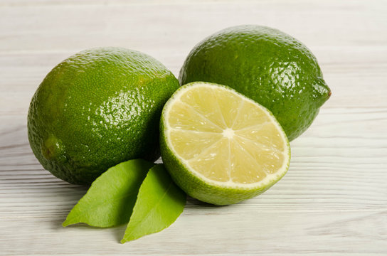 two lemons with half of  juicy lime on a wooden table